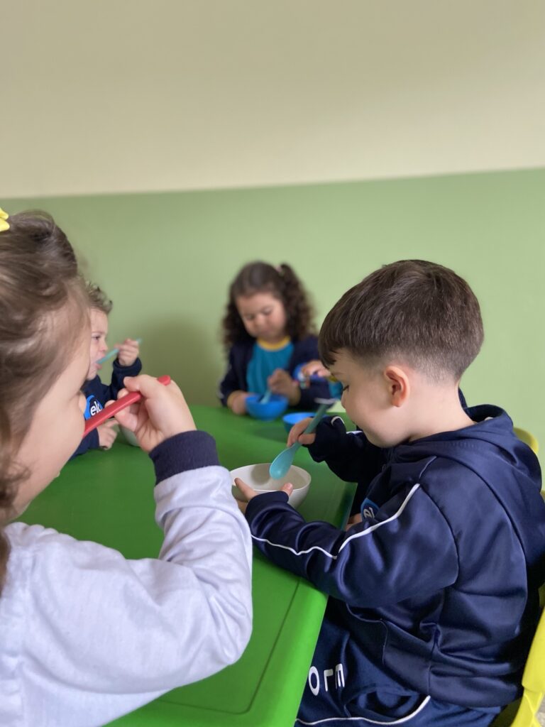 Duas crianças interagindo durante a refeição na mesa da escola