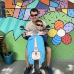Pai com criança em frente ao mural colorido do evento Dia das Mães