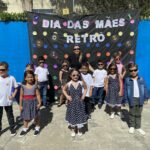 Grupo de crianças no painel decorado do evento Dia das Mães Retrô