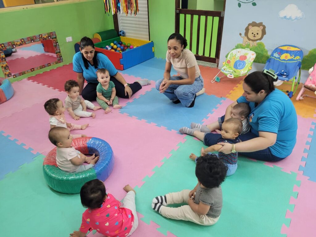 Bebês em tapete colorido com a professora na sala do berçário