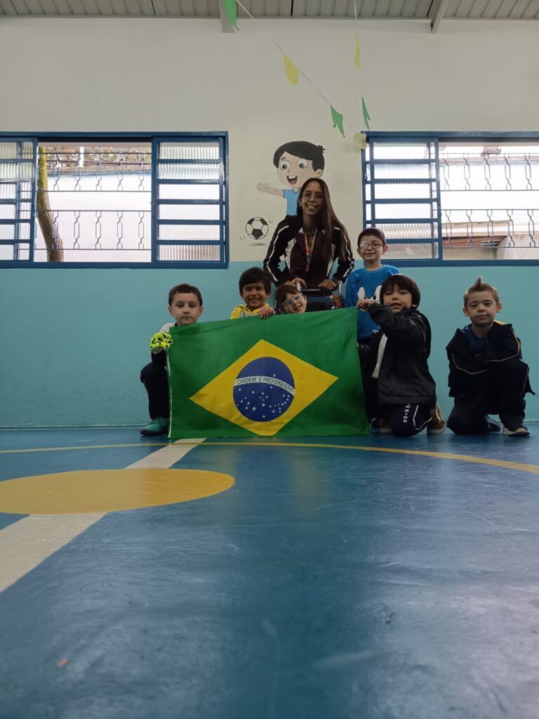 Time de futebol da escola posando com a bandeira do Brasil