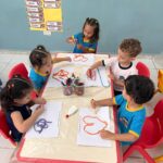 Criança confeccionando arte com barbante colorido durante aula de leitura