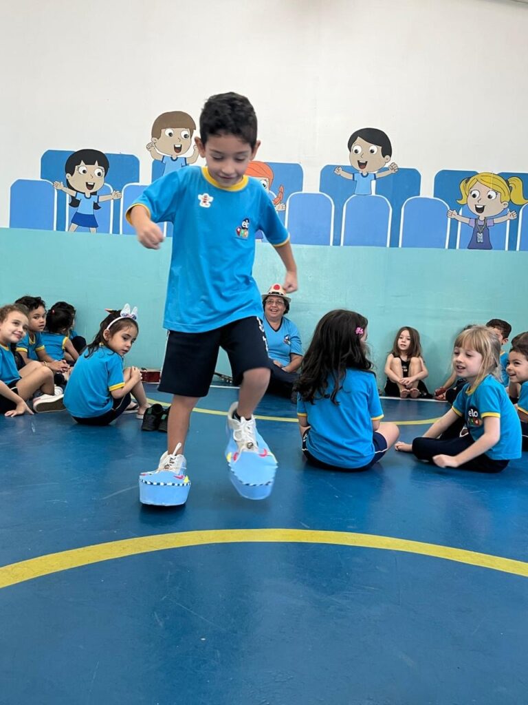 Criança se apresentando em pé diante da turma sentada na aula de musicalização